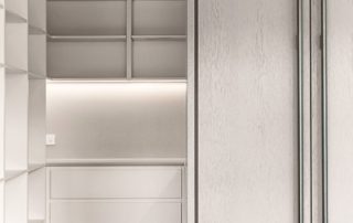 Architectural Precision: A Bespoke Walk-In Pantry Modern walk-in pantry with floor-to-ceiling white cabinetry, clean lines, ample shelving, and integrated refrigerator, showcasing precision joinery and architectural design.