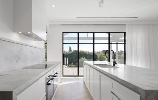 Excellence in Kitchen Joinery and Design A luxurious kitchen showcasing a bespoke island, white custom cabinetry, and elegant dolomite stone benchtops, complemented by seamlessly integrated appliances.