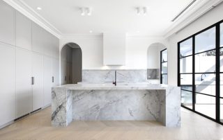 Architectural Joinery | Bespoke Kitchen Cabinetry Contemporary luxury kitchen with Oyster Gray Matte cabinetry, a Super White Dolomite waterfall island, and a neutral palette accented by black glass frames.