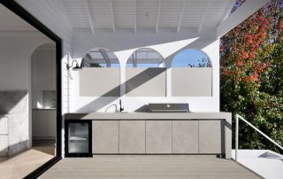 Luxury Outdoor Kitchen with BBQ and Bespoke Joinery A luxury outdoor BBQ kitchen with 'oyster gray matte' cabinetry, a built-in BBQ, integrated fridge, and sink.