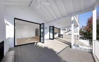 Luxury Outdoor Living: Architectural Joinery Masterpiece High-end minimalist patio with bespoke oyster gray matte finish joinery outdoor kitchen, integrated BBQ and fridge, framed by round arches. The French doors are open showing indoor outdoor design.