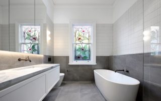 Luxury Bathroom | Classic White Matt Vanity Luxury bathroom with custom-built vanity featuring a classic matte white finish, double sink, brass tapware, and a stained glass window.