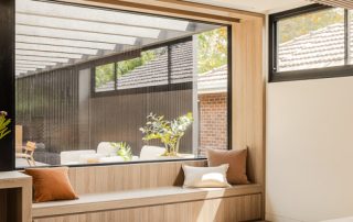 Architectural Joinery | Bespoke Window Bench-Seat A contemporary master bedroom with a custom integrated window bench-seat with a Maison Oak Ravine finish. The window seat has integrated storage with sharknose fingerpull, soft-close drawer. The window seat overlooks a luxury outdoor entertaining area.