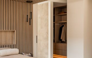 Bespoke Walk-In Wardrobe | Architectural Joinery Custom walk-in wardrobe with bespoke joinery in a warm neutral palette, featuring 'Maison Oak Ravine' finish, integrated lighting, and soft-close drawers.