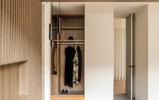 Architectural Joinery | Bespoke Walk-In Wardrobe Custom walk-in wardrobe with a Maison Oak Ravine finish, integrated lighting, and storage including shelves, hanging space, and soft-close drawers.