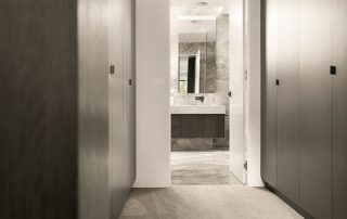 Modern Ensuite Glimpse | Black Wenge Ravine Wardrobe Doors View through to modern ensuite bathroom from a master bedroom, showcasing bespoke cabinetry on the vanity in a Black Wenge Ravine finish, and wardrobe doors.