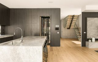 Premium Materials and Design | Modern Kitchen A luxury, modern home featuring floor-to-ceiling cabinetry in a rich, charcoal finish with a fully-integrated wine cellar.
