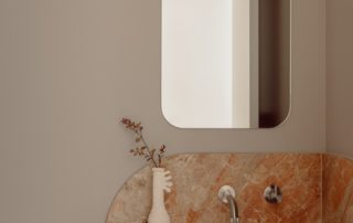 Hampton Residence – Ensuite Vanity Custom ensuite vanity with sculpted stone benchtop, wall-mounted tapware, and custom cabinetry in a soft maple finish.
