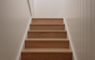 Hampton Residence – Interior Staircase Modern timber staircase with vertical white balustrade and clean architectural lines in a bright interior.