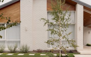 Hampton Residence – Exterior Contemporary residential exterior with white brickwork, timber-lined gabled roof, and landscaped entry garden.